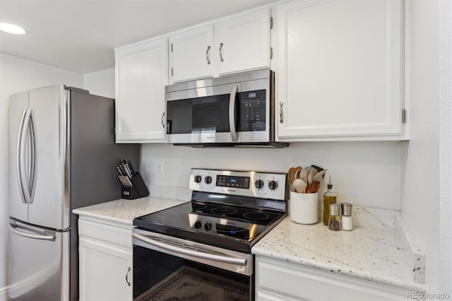 kitchen with stainless steel appliances, light stone countertops, and white cabinetry