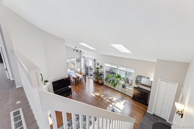 living room featuring lofted ceiling with skylight, wood finished floors, visible vents, and baseboards