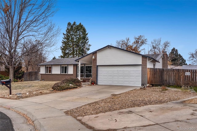 view of front of property with brick siding, driveway, a garage, and fence