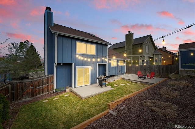 3593 S Gibralter Cir, Aurora, CO 80013 - back of property at dusk featuring board and batten siding, a chimney, and a patio area