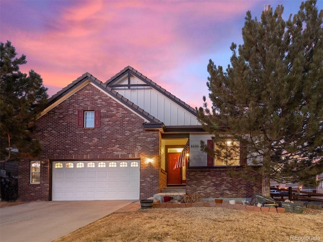 view of front of home featuring concrete driveway, a tile roof, a front lawn, board and batten siding, and brick siding