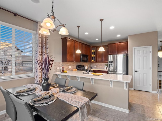 kitchen with a peninsula, black appliances, glass insert cabinets, and light countertops