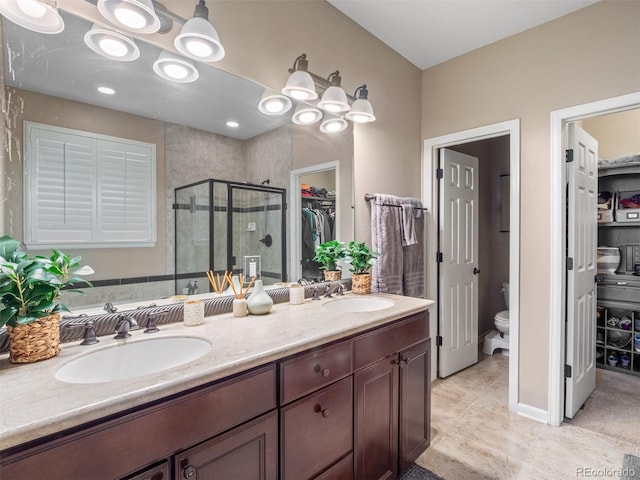 full bath featuring toilet, a stall shower, a walk in closet, and a sink