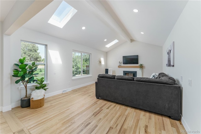 living room with light hardwood / wood-style flooring and vaulted ceiling with skylight