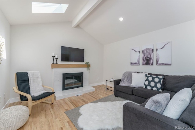 living room with a tiled fireplace, lofted ceiling with skylight, and hardwood / wood-style floors