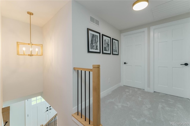 corridor with light carpet and an inviting chandelier