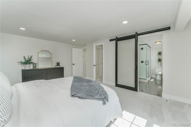 bedroom with light carpet, a barn door, and ensuite bathroom