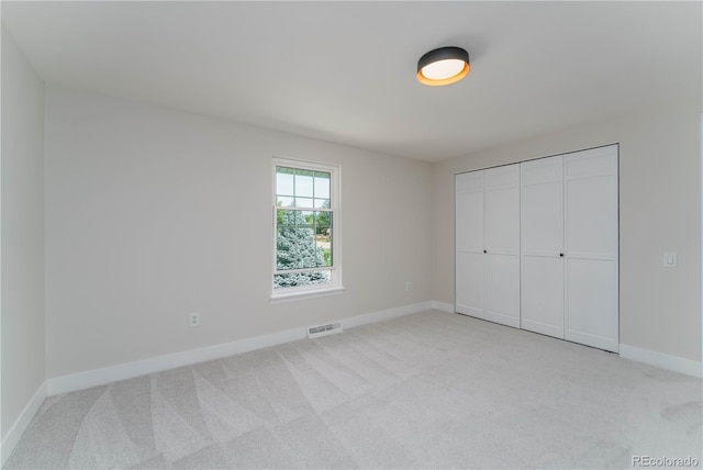 unfurnished bedroom featuring light carpet and a closet