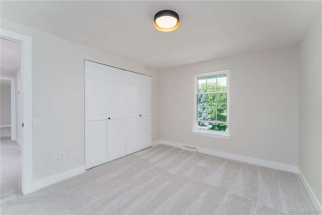 unfurnished bedroom with a closet and light carpet