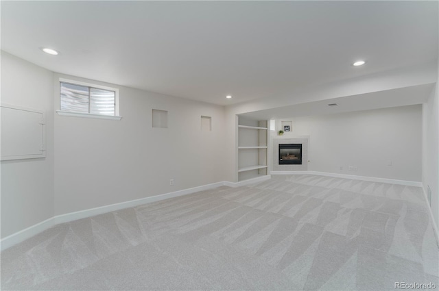 basement featuring light carpet, built in features, and a fireplace