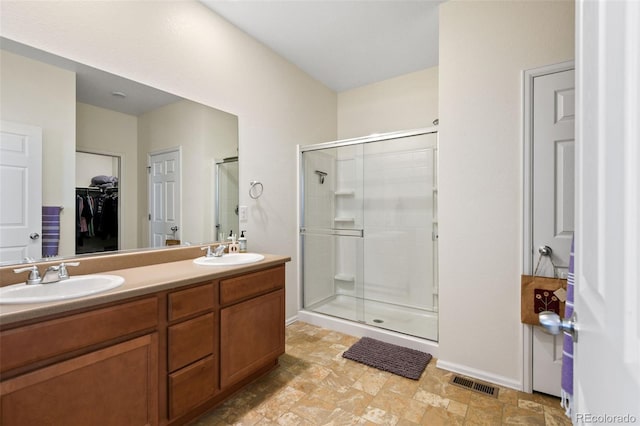 full bathroom featuring double vanity, visible vents, a shower stall, and a sink