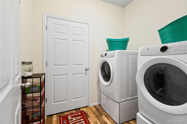 clothes washing area with laundry area, light wood-style floors, and washing machine and clothes dryer