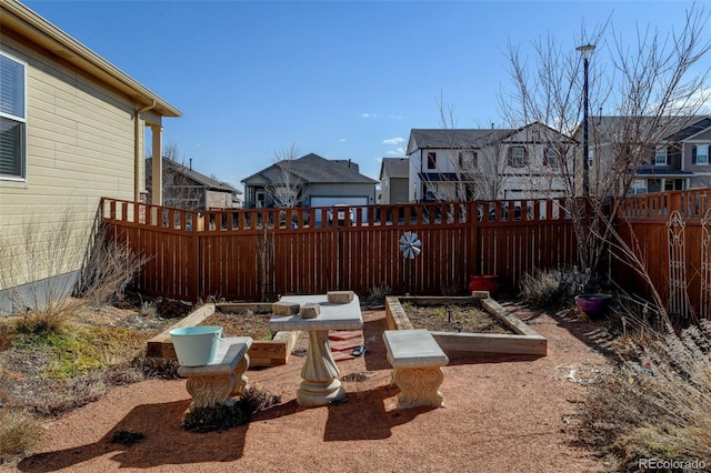 view of yard featuring a vegetable garden, a residential view, and a fenced backyard