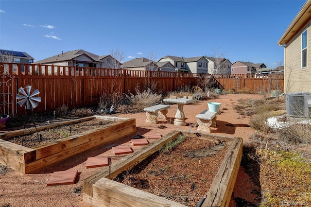 view of yard featuring a residential view, central air condition unit, fence private yard, and a vegetable garden