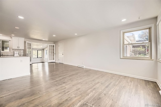 unfurnished living room with light wood-style flooring, recessed lighting, and baseboards