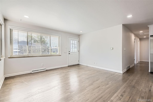 unfurnished living room with a baseboard radiator, wood finished floors, baseboards, and recessed lighting