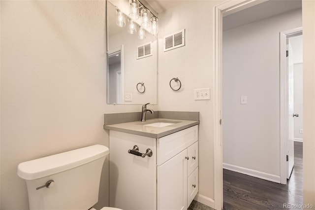 half bathroom featuring wood finished floors, vanity, toilet, and baseboards