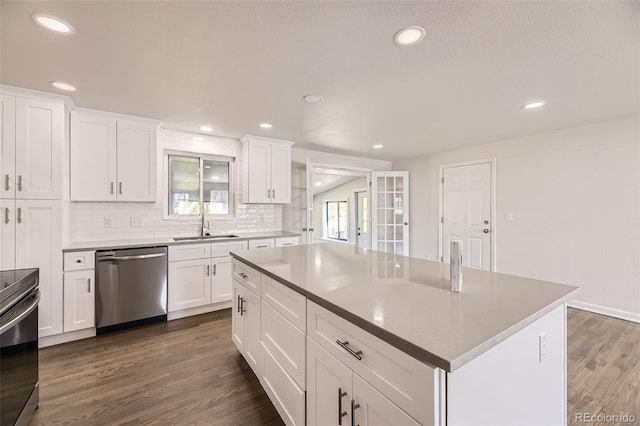 kitchen with stainless steel appliances, a sink, dark wood-type flooring, white cabinetry, and recessed lighting