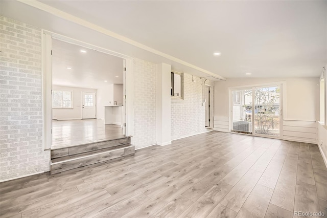 unfurnished living room with wood finished floors and brick wall