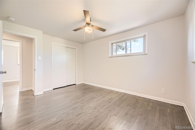 unfurnished bedroom featuring baseboards, wood finished floors, a closet, and ceiling fan