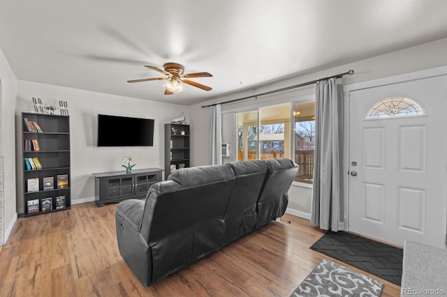 living area featuring ceiling fan, baseboards, and wood finished floors