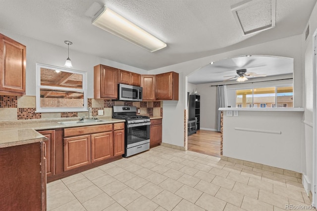 kitchen with arched walkways, stainless steel appliances, a sink, and light countertops