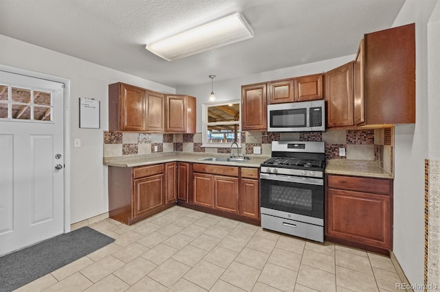 kitchen featuring stainless steel appliances, a sink, light countertops, and brown cabinets