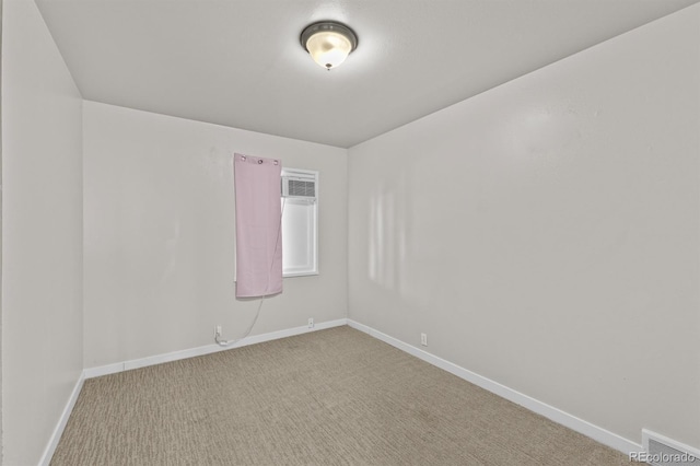 empty room with carpet, visible vents, and baseboards