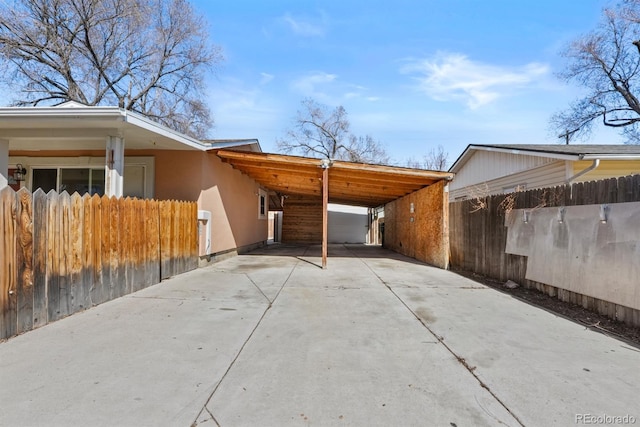 exterior space featuring a carport, fence, and driveway