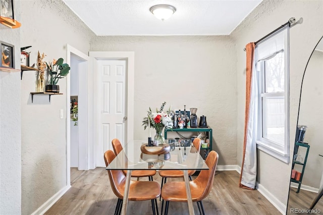 dining room with a textured ceiling and light hardwood / wood-style floors