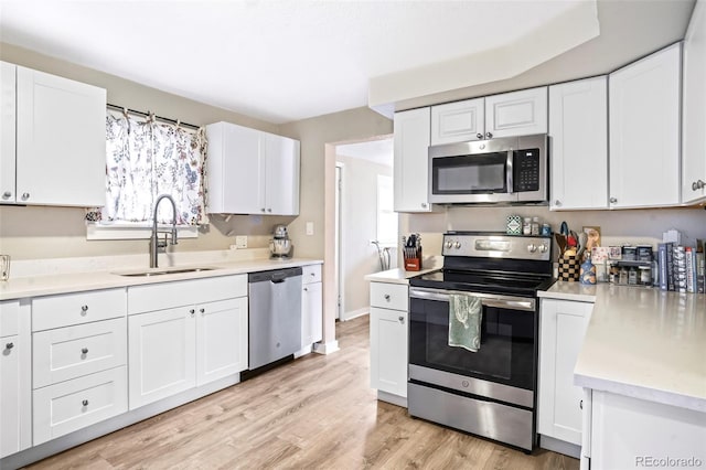 kitchen with light hardwood / wood-style flooring, sink, stainless steel appliances, and white cabinetry