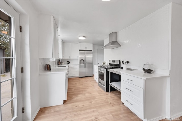 7131 Clay St, Westminster, CO 80030 - kitchen with wall chimney range hood, stainless steel appliances, a sink, light wood finished floors, and light countertops