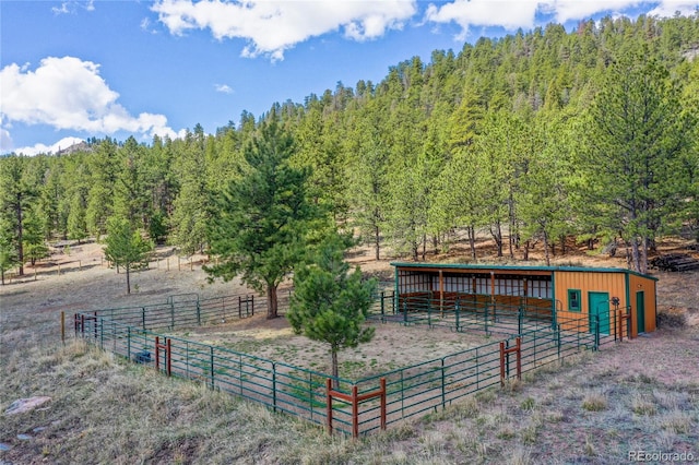 horse barn featuring a view of countryside and a view of trees