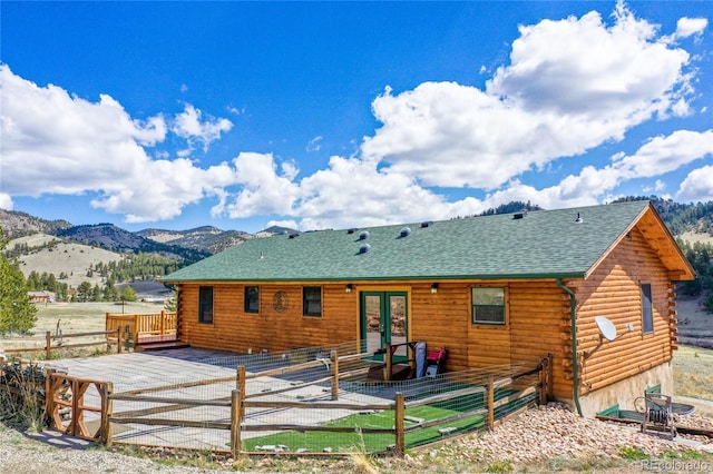 back of property with french doors, a deck with mountain view, log siding, and fence