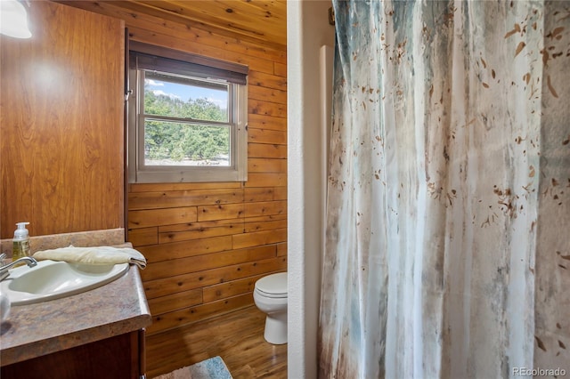 full bath featuring toilet, vanity, wood finished floors, wood walls, and a shower with shower curtain