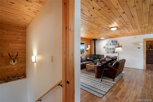 living area featuring wooden ceiling, wood finished floors, a wood stove, and wood walls