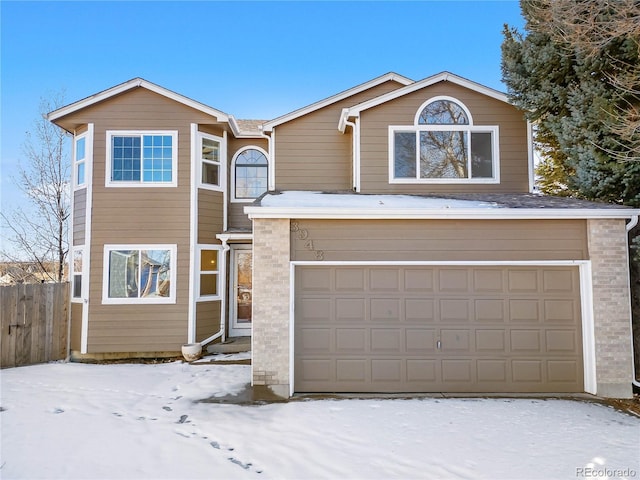 traditional-style home featuring brick siding, an attached garage, and fence