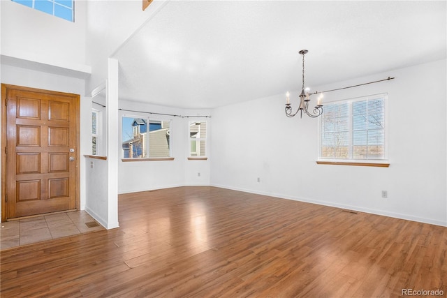 foyer with baseboards, plenty of natural light, wood finished floors, and an inviting chandelier