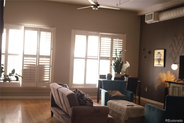 living area with light wood-style floors, ceiling fan, and baseboards