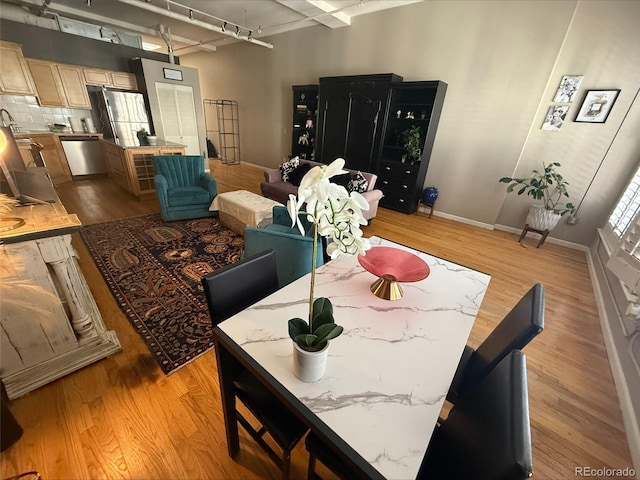 dining space featuring track lighting, light wood-style flooring, and baseboards