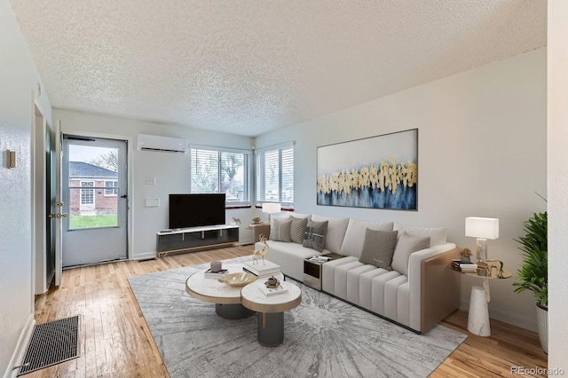 1525 Xenia St, Denver, CO 80220 - living area featuring light wood finished floors, visible vents, an AC wall unit, and a textured ceiling