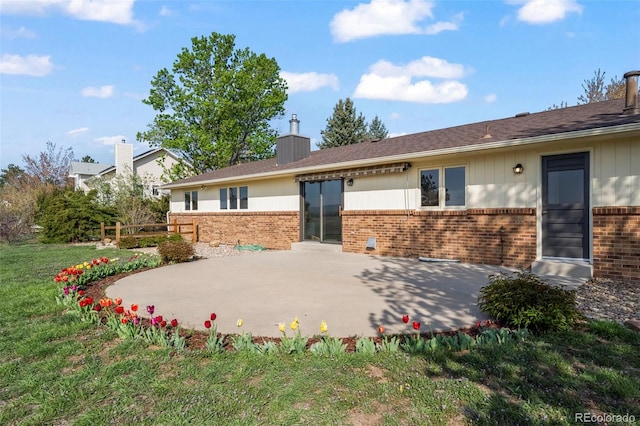 1198 Crestmoor Dr, Boulder, CO 80303 - back of house featuring brick siding, a patio, a yard, and a chimney