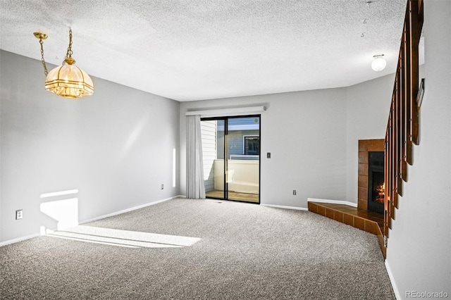 carpeted spare room with a tile fireplace and a textured ceiling