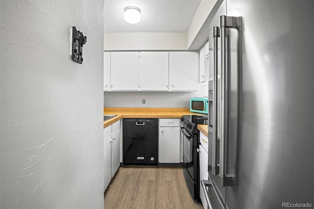 kitchen featuring butcher block counters, white cabinetry, a textured ceiling, black appliances, and light wood-type flooring