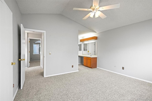 unfurnished bedroom with a textured ceiling, ceiling fan, light colored carpet, and lofted ceiling