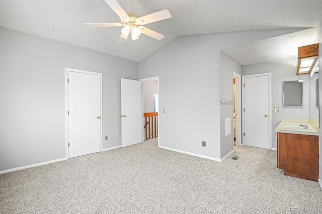 unfurnished bedroom featuring ensuite bathroom, ceiling fan, light carpet, and vaulted ceiling