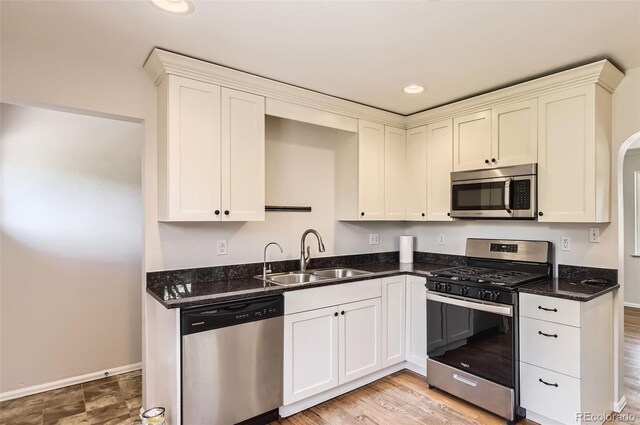 4111 S Delaware St, Englewood, CO 80110 - kitchen featuring stainless steel appliances, dark stone counters, white cabinets, recessed lighting, and arched walkways