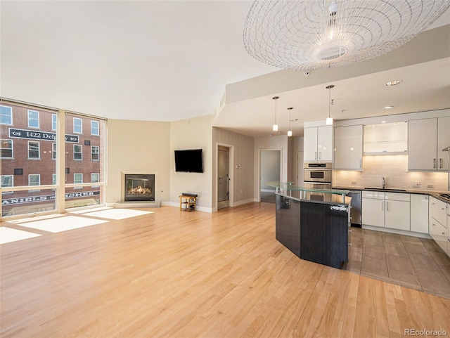 kitchen featuring pendant lighting, decorative backsplash, white cabinetry, and sink