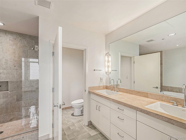 bathroom with vanity, toilet, and tiled shower