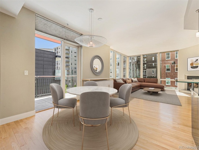 dining space with a chandelier, light hardwood / wood-style flooring, and a wall of windows